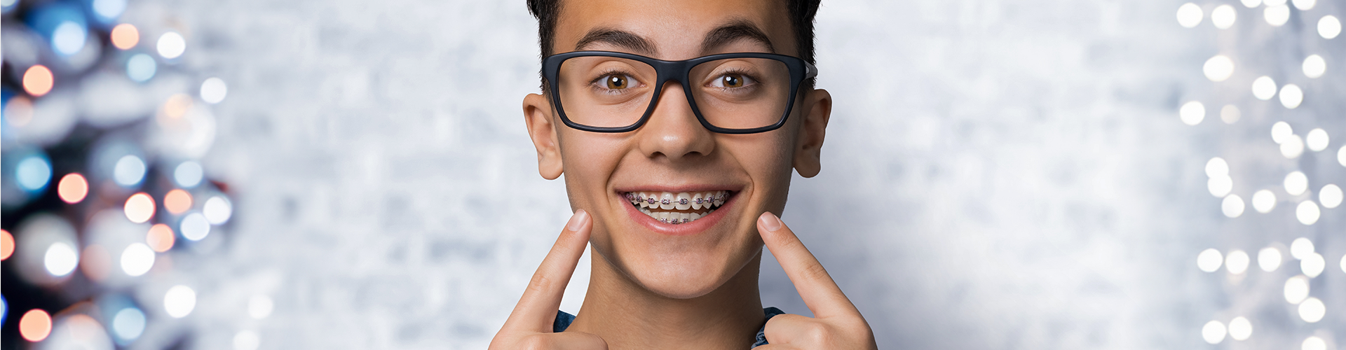 smiling teen pointing at his braces